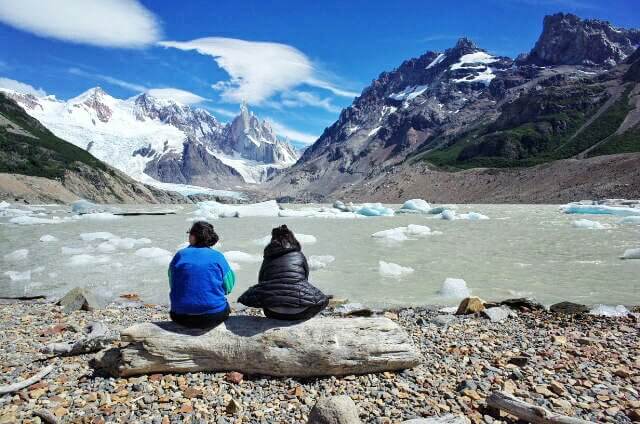 Two sitting on a tree log watching Laguna Torre Fritz Roy